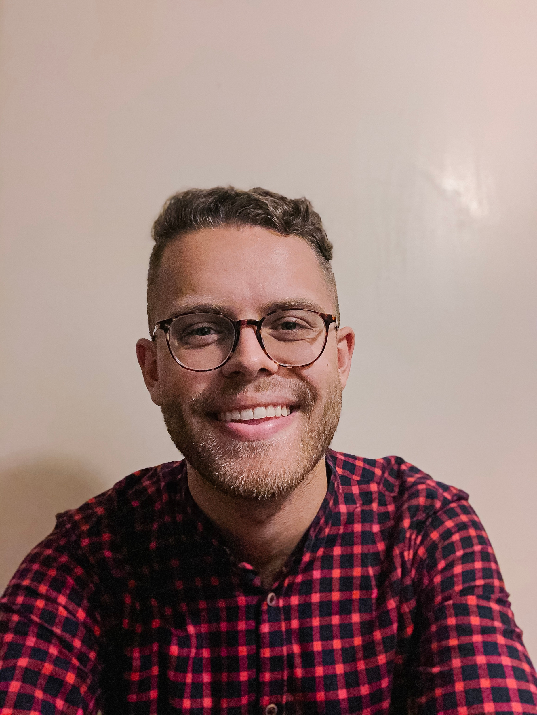 Portrait picture of Jacob, smiling at the camera wearing a black and red shirt.