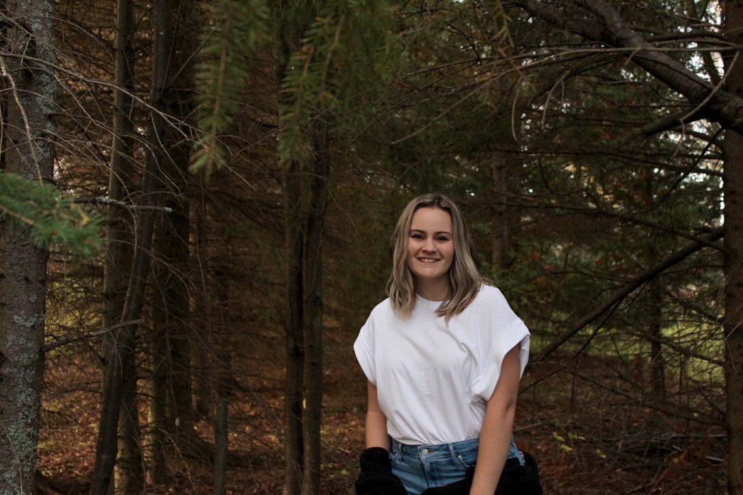 Picture of Kianna, smiling and posing outdoors with a white t-shirt and blue jeans