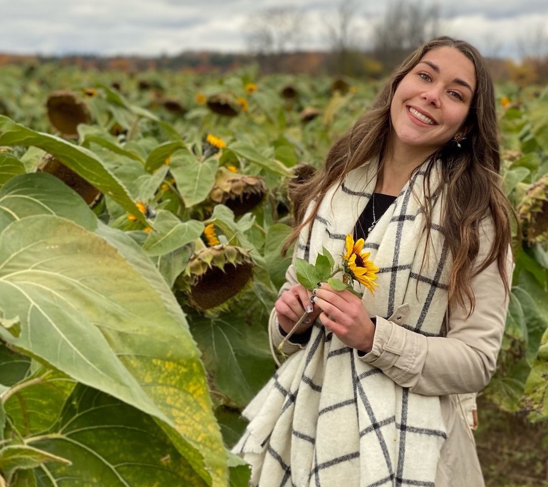 Alana standing in a flower field, smiling