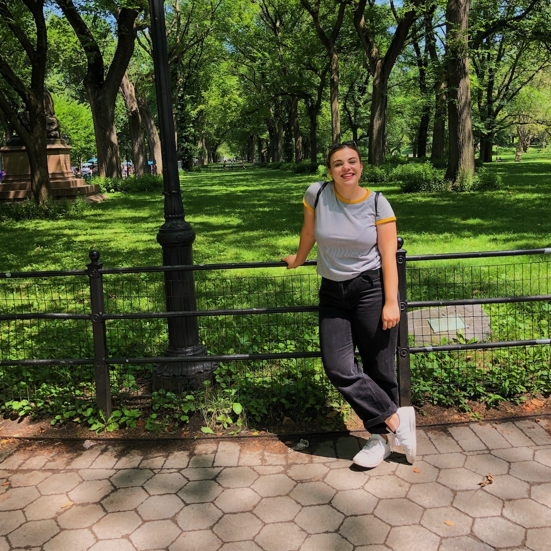 Image of Rachel in a park, leaning on a fence.