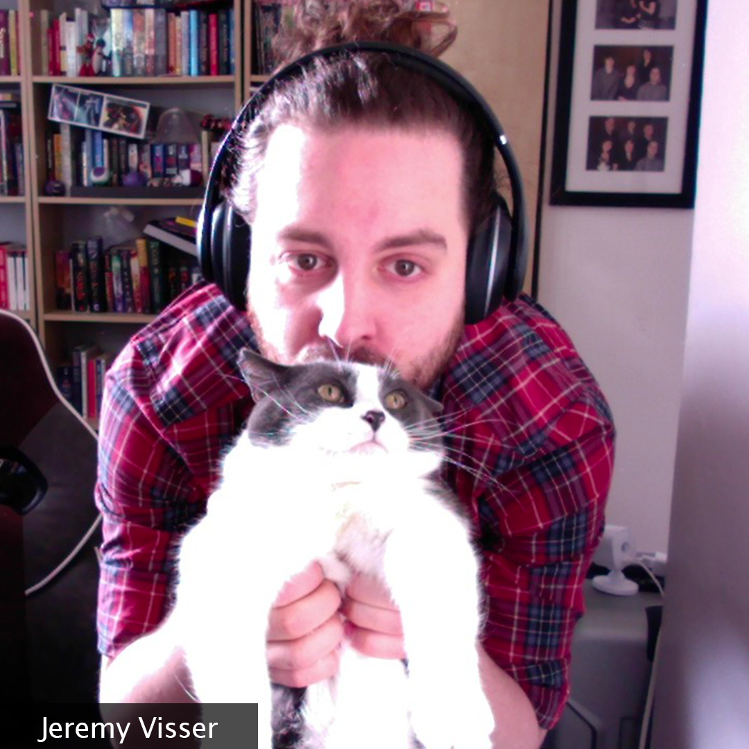 A man with a bun in his home office smooching his cat and partner in crime, Artemis