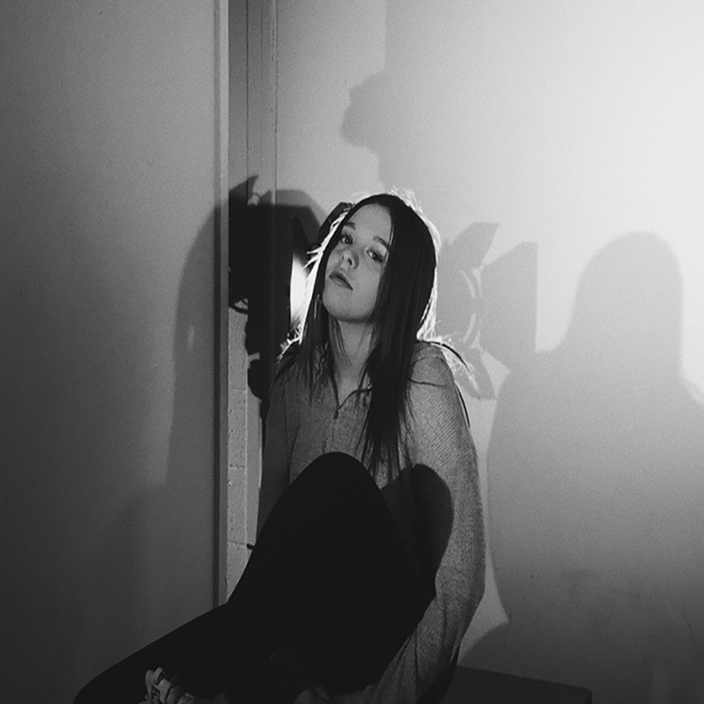 Black and white picture of Abby sitting against a wall