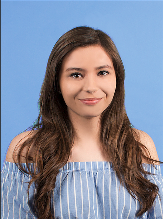 Headshot of Ariana, smiling to the camera and wearing a blue and white shirt