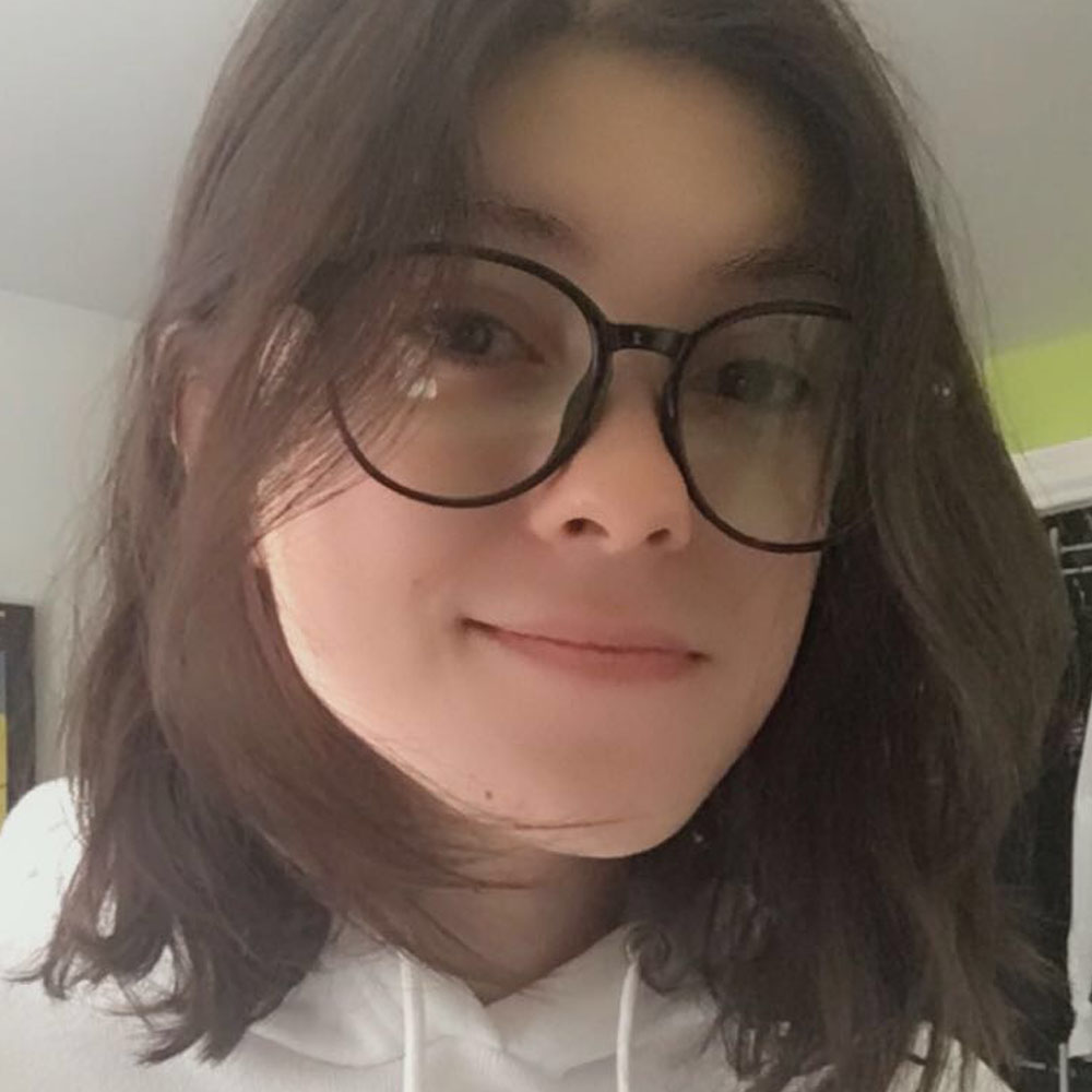 Celina DaSilva posing for the camera, wearing a white blouse and glasses