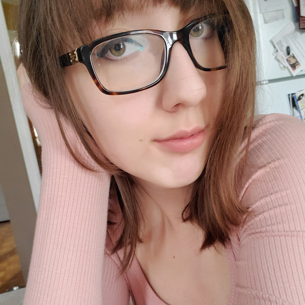 Picture of Monika, wearing a light rose pink shirt and glasses