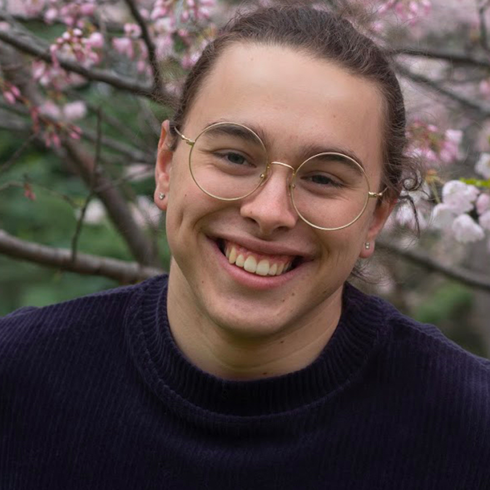 Outdoors picture of Robert, smiling to the camera and wearing a navy blue sweater