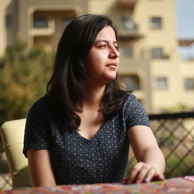 Shifa Naseer's side portrait, sitting on a chair with a hand on the table.