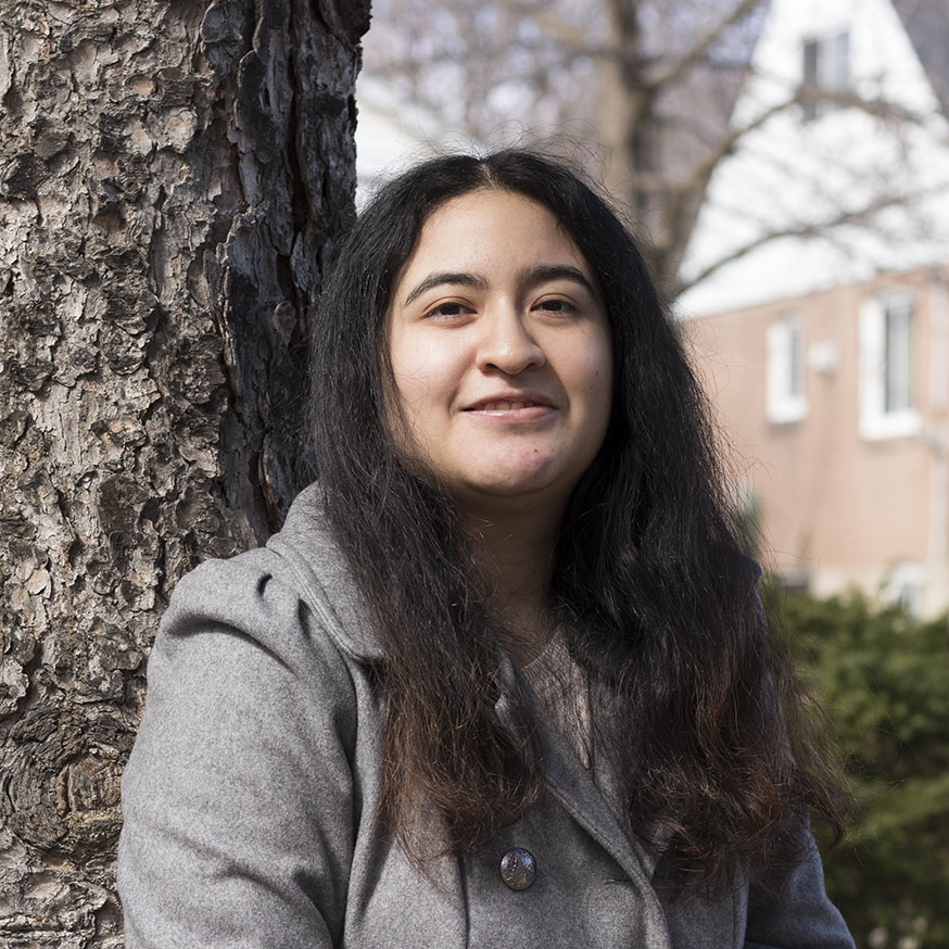 This is a headshot image of Jezebel Torres. She is wearing a grey coat and is standing against a tree.