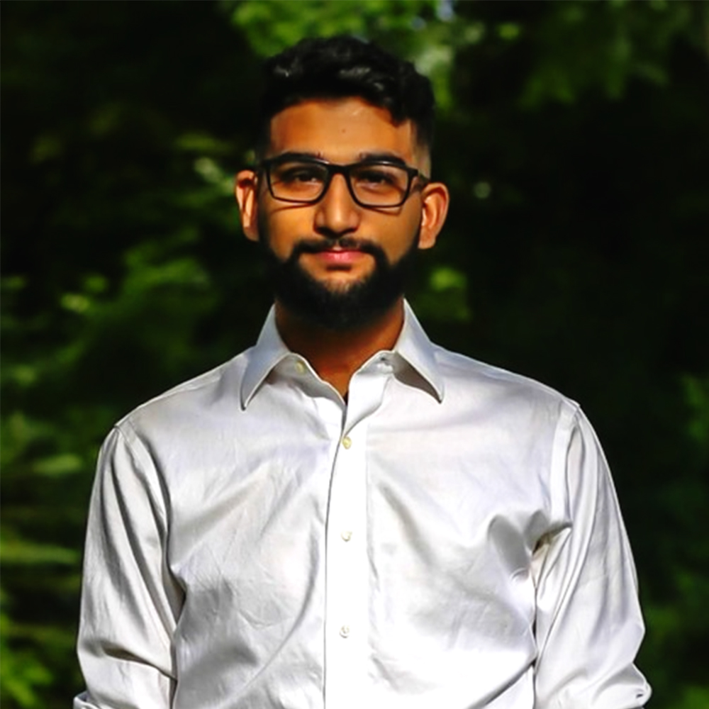 Picture of Christopher Pinto, outdoors and wearing a white shirt