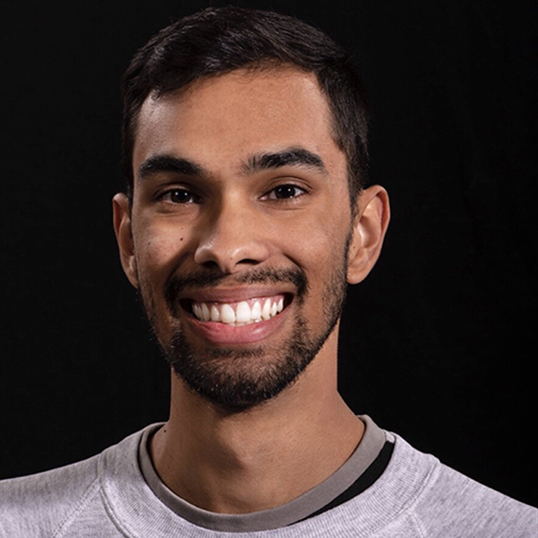 A professional headshot, Grey long sleeve shirt, smiling, black hair,