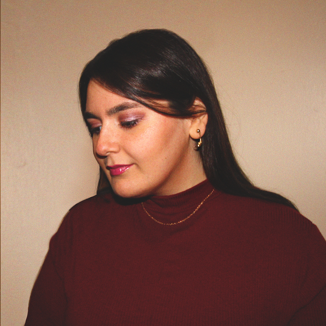 Vall Fierro, a woman with long brown hair in 3/4 view looking down to the left wearing a burgundy turtleneck