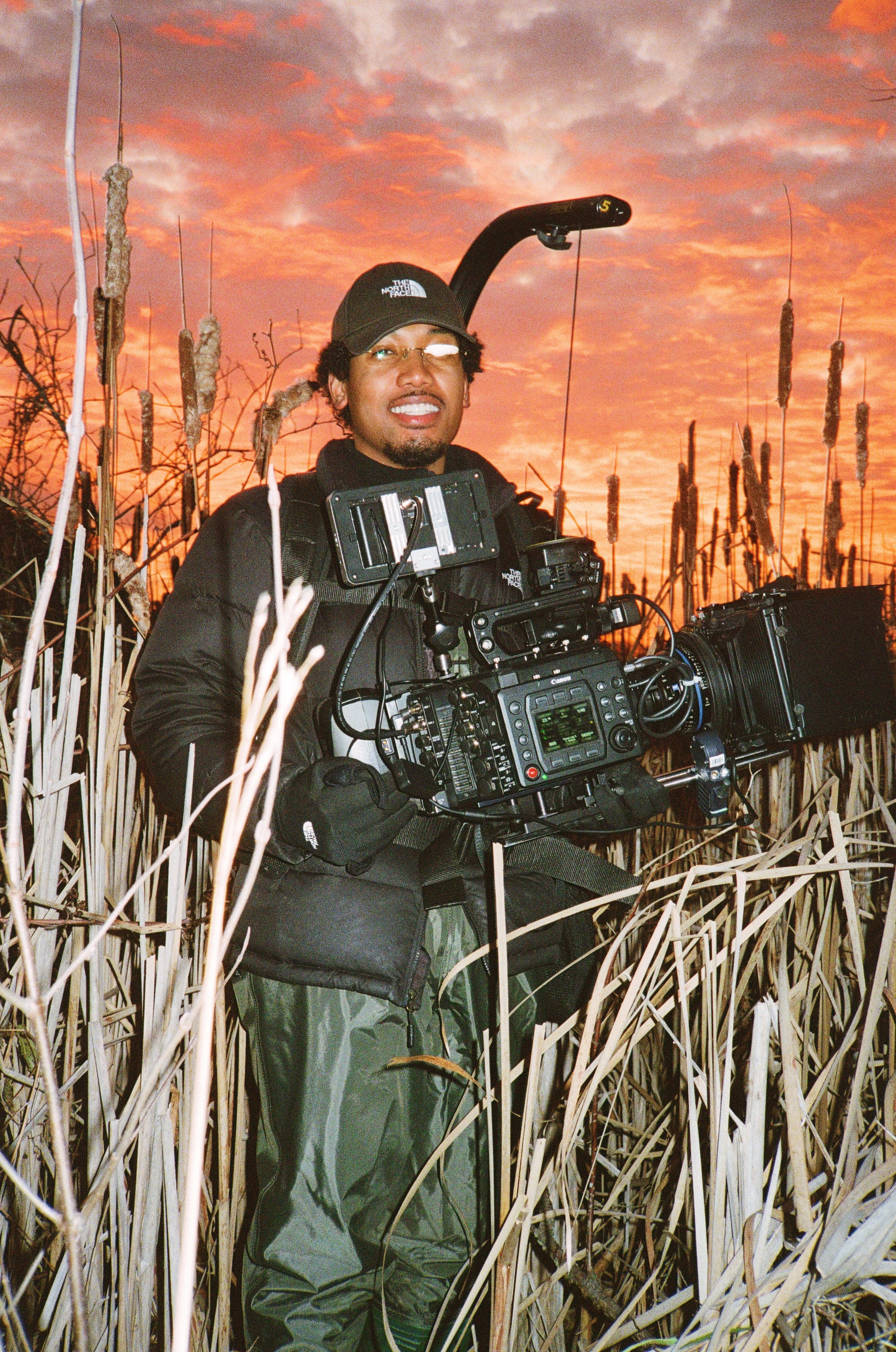 FMTV student Joel Mens, standing in a marsh wearing waders and a Steadicam rig.