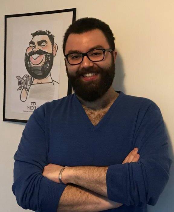 A smiling Rezayar Mehrpour stands cross-armed and alongside a caricature drawing of himself holding a camera.