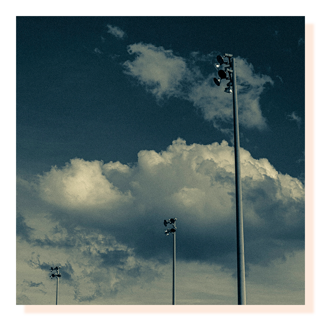 Exterior lamp posts shot looking up and framed against a cloudy sky backdrop.