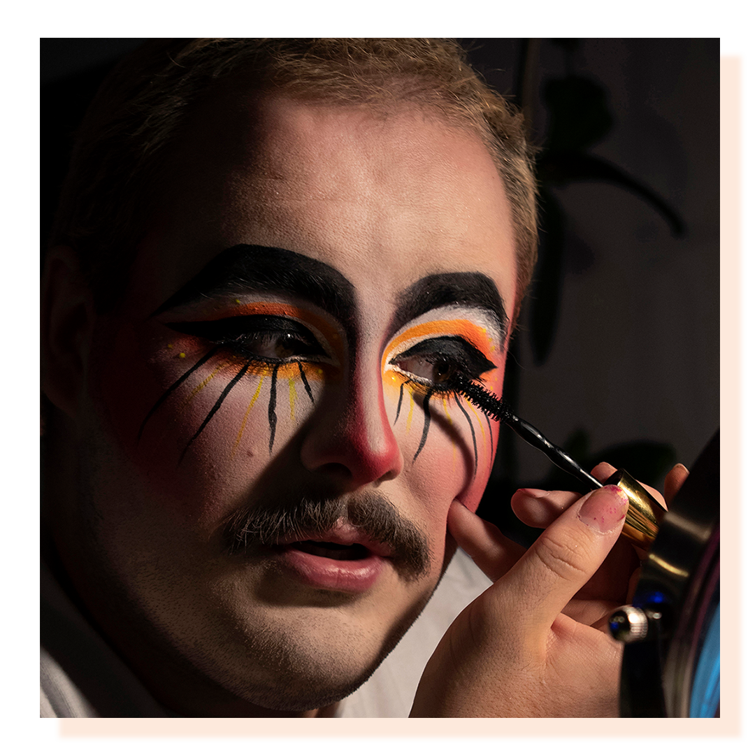 A close up shot of a man’s face applying clown makeup.