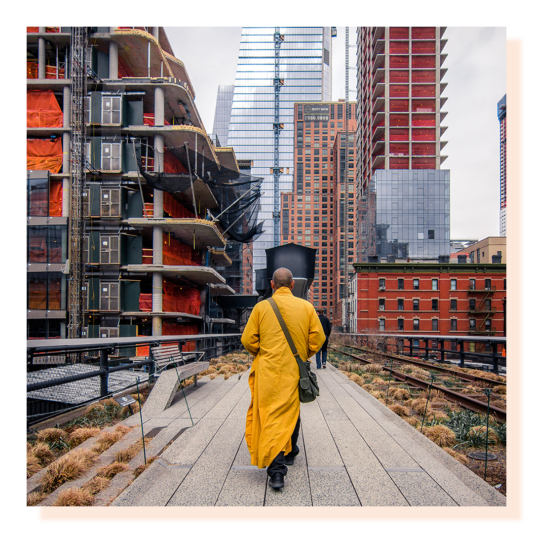 Man walking between two tall buildings wearing a yellow robe.