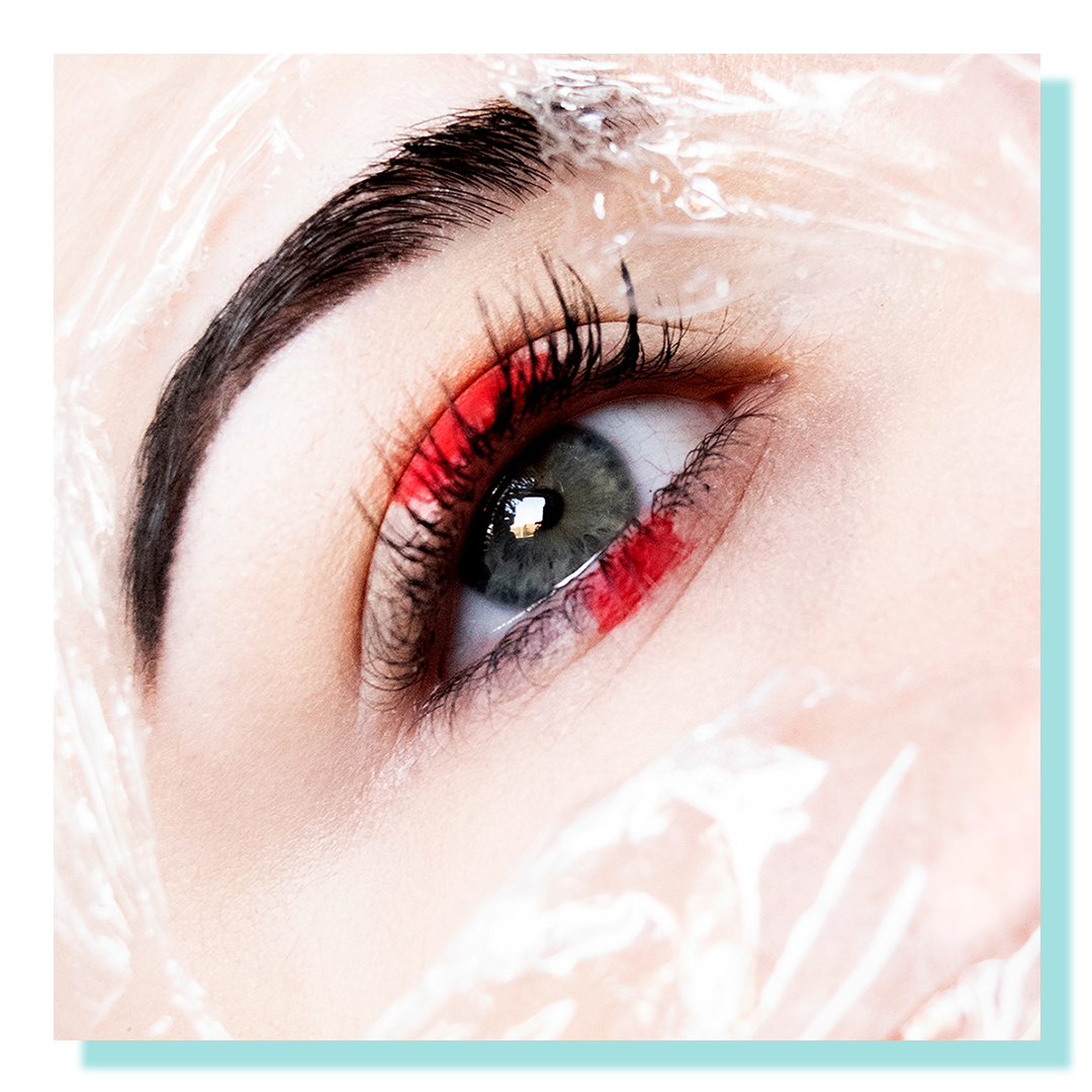 Close up of an eye with saran wrap and red makeup.