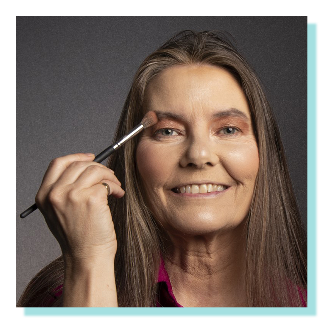 Woman holding makeup brush close to face.