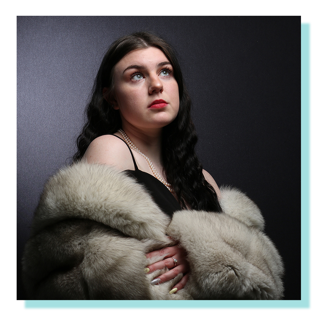 Woman with fur coat posing looking up.