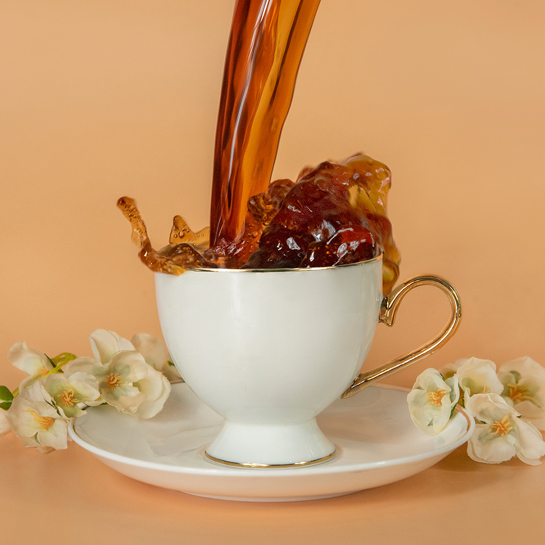 Tea splashing in white cup and saucer placed on a plain coloured beige background.