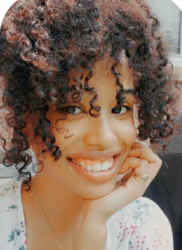 Justine smiling with hand under chin.