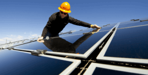 Un Installateur pose des panneaux solaires sur support au sol.