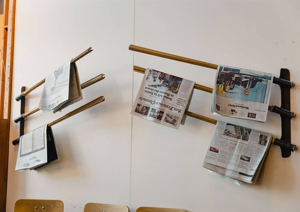 Newspapers on a rack attached on a white wall