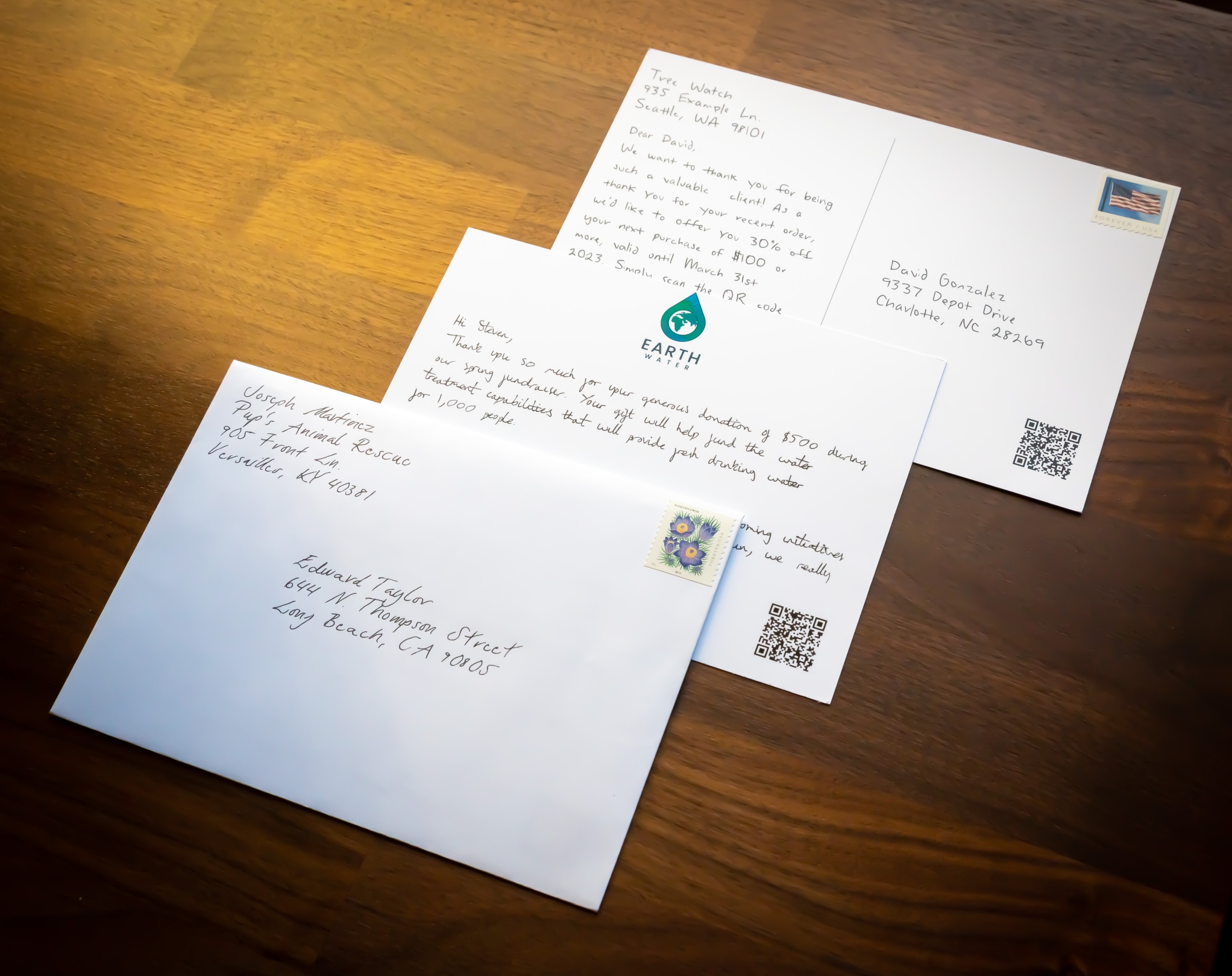 a handwritten letter, handwritten post card, and hand written card + handwritten envelope on a table
