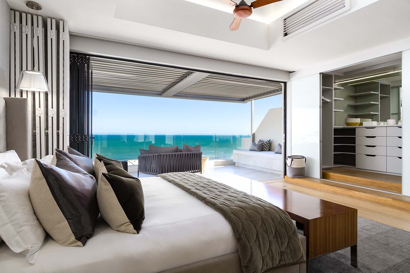 In the master bedroom, fold-away shutter doors reveal a balcony with seating area.