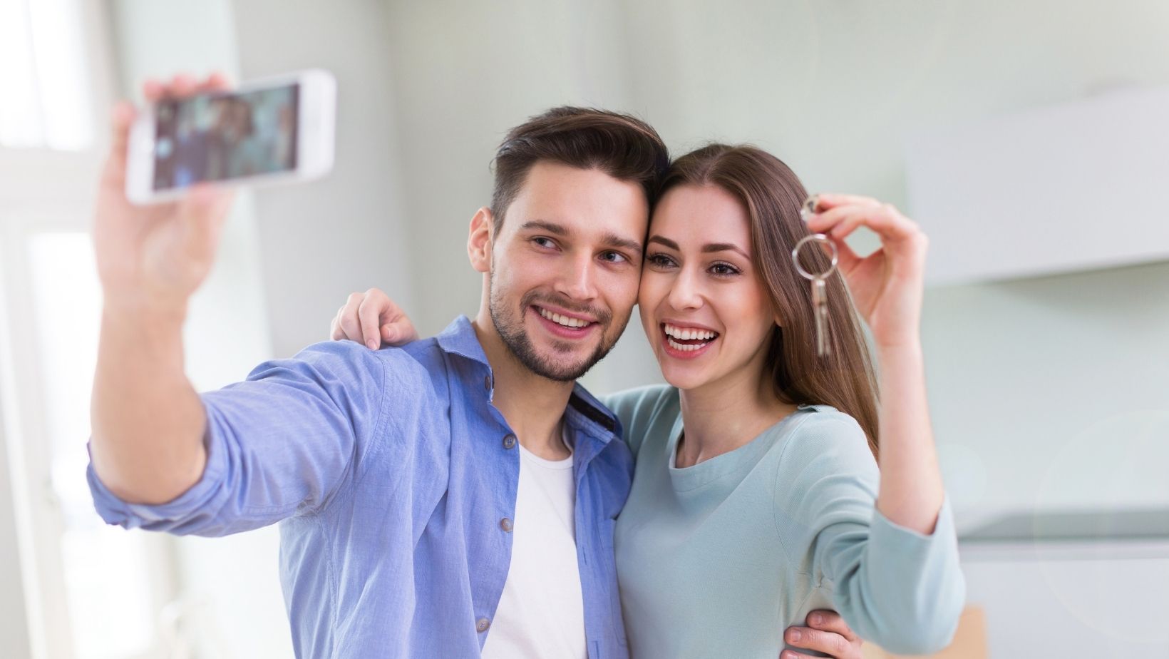 couple taking selfie with keys to new home