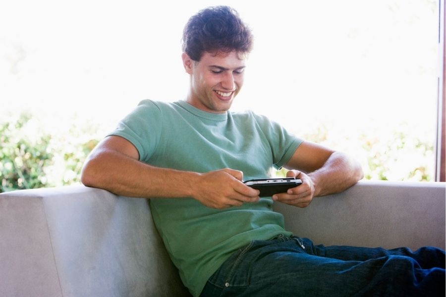 young man on couch with hand-held gaming system