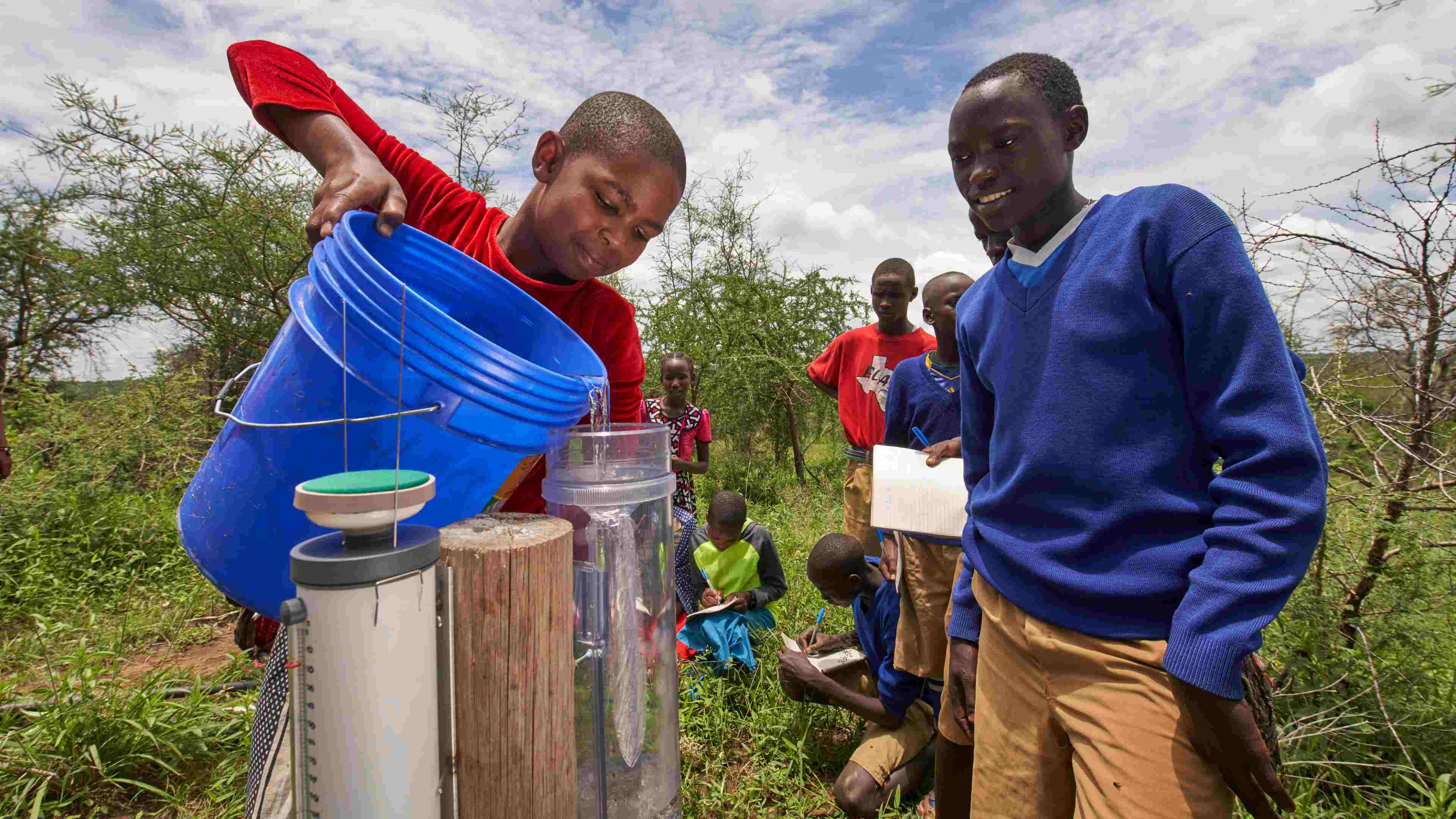 Group of young students using a rain gauge