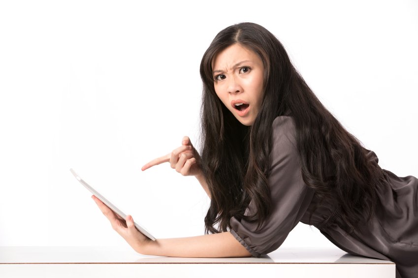 Shocked woman pointing at her digital-tablet.