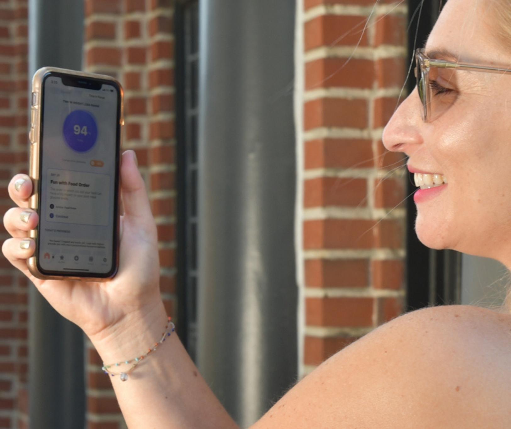 woman holding smartphone in front of her face and smiling
