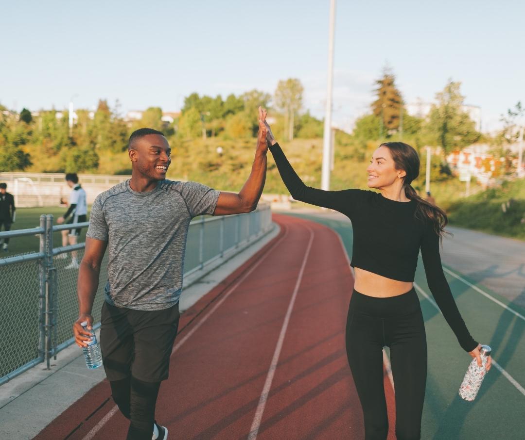 a man and a woman giving each other a high-five on a running track