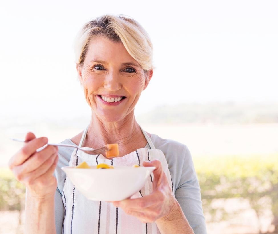 Older woman showing off a bowl of fresh fruits
