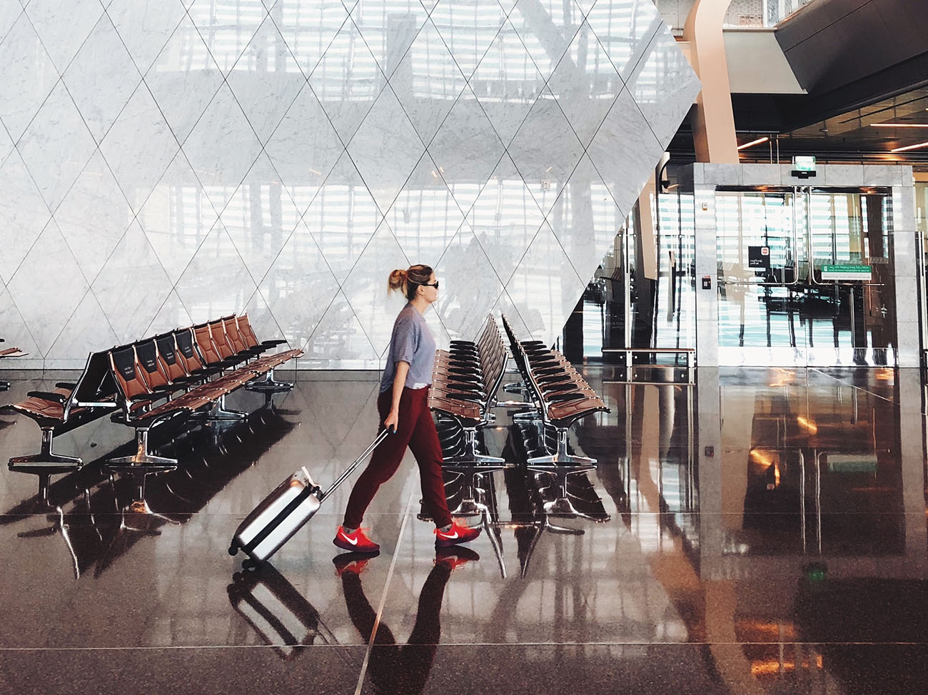 Frau läuft mit Koffer und roten Schuhen in Flughafen