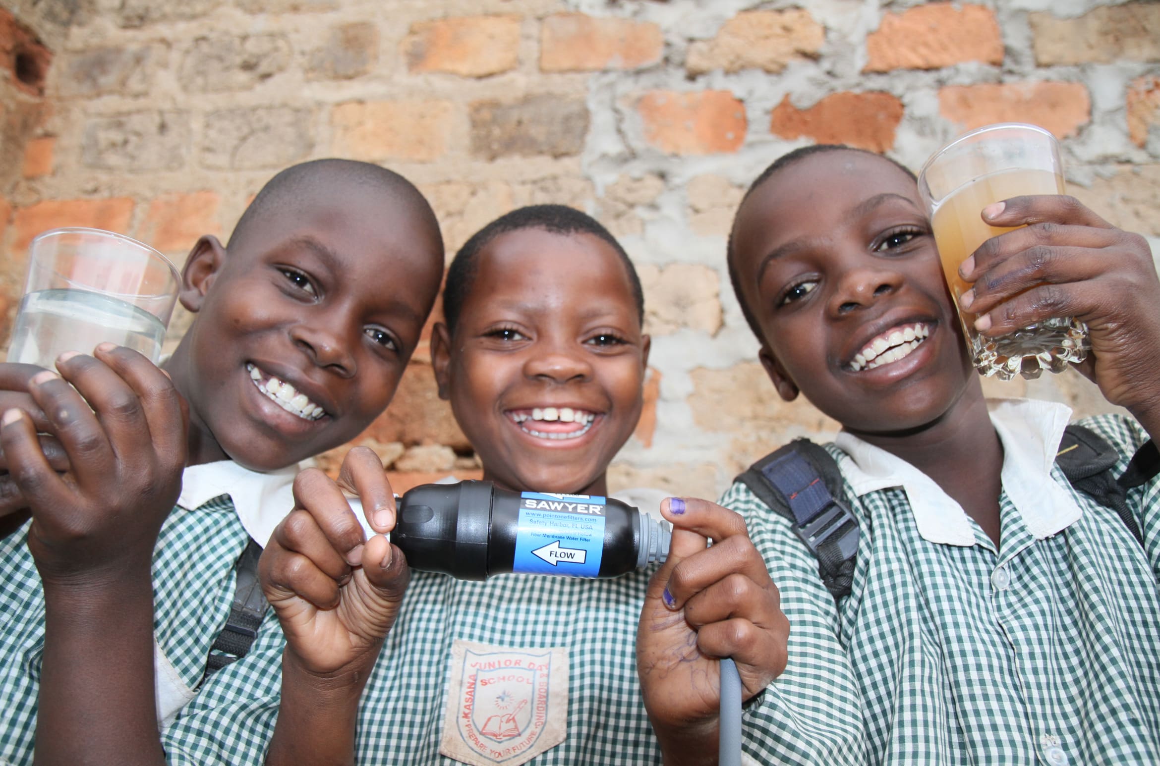Three children use a Sawyer filter as part of an international project.