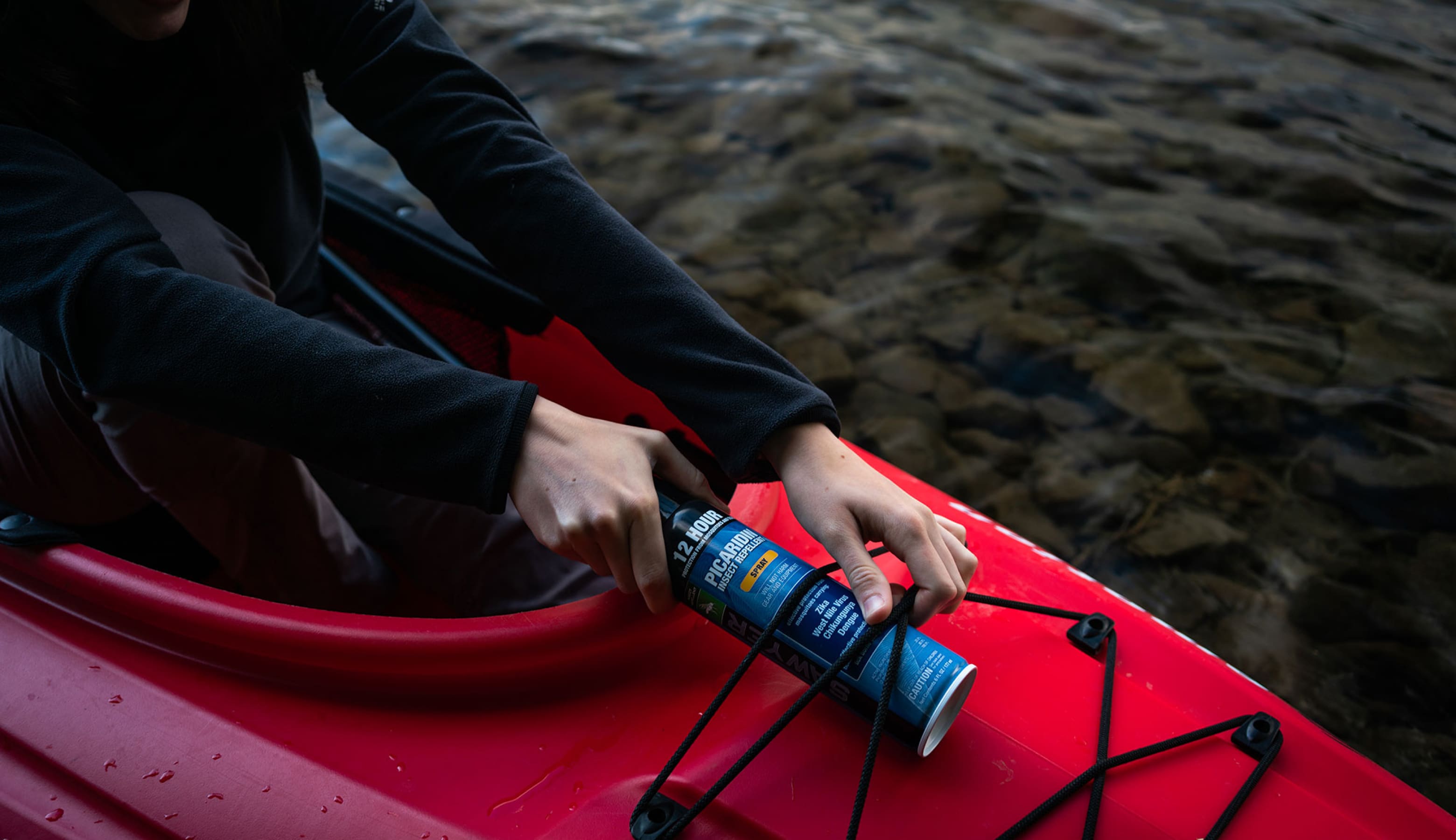 A canoeist ties Sawyer Insect Repellent into a canoe.