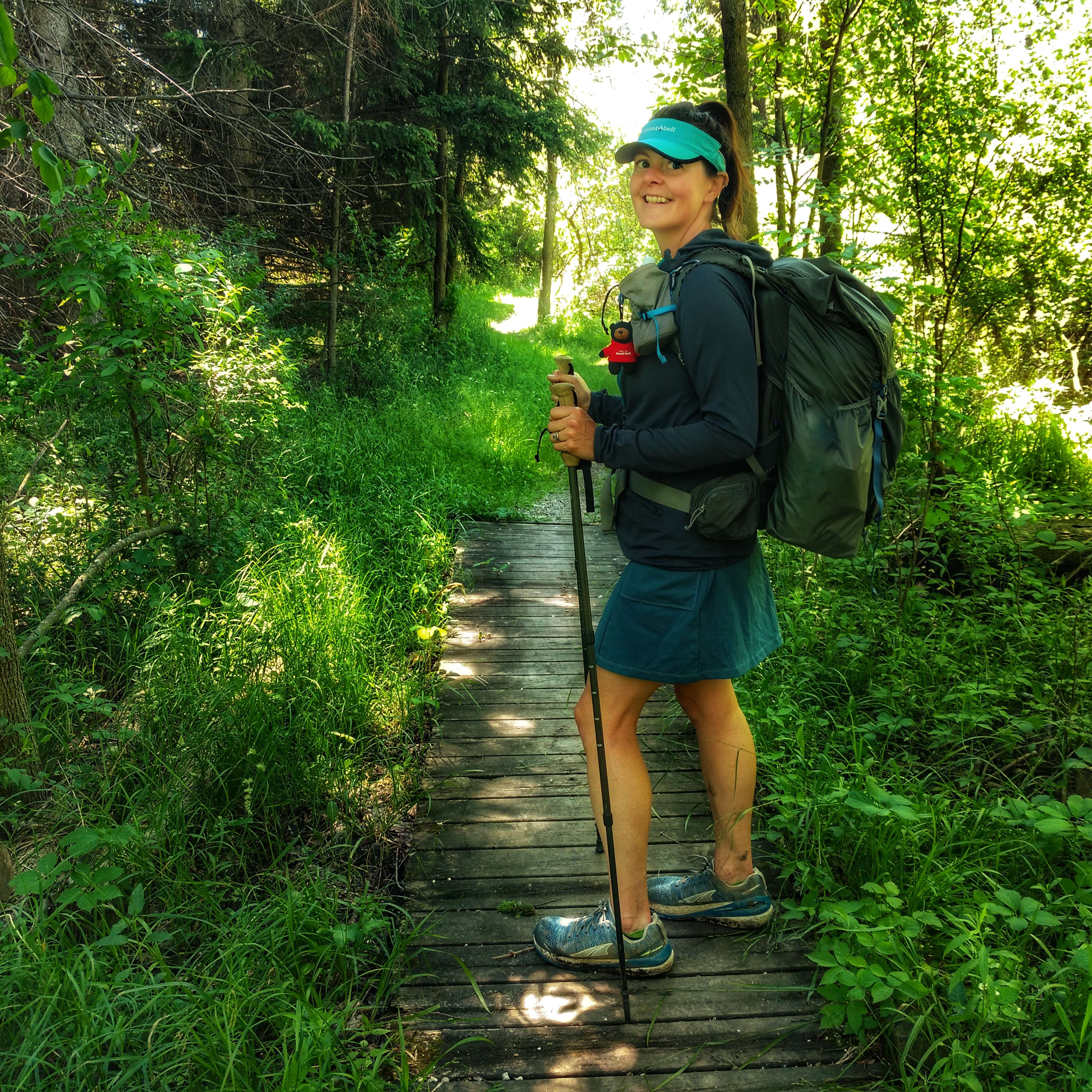 A picture of a woman hiking in green forest