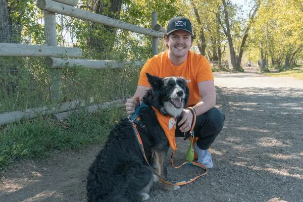 Male dog walker posing with a dog in a park on a pathway