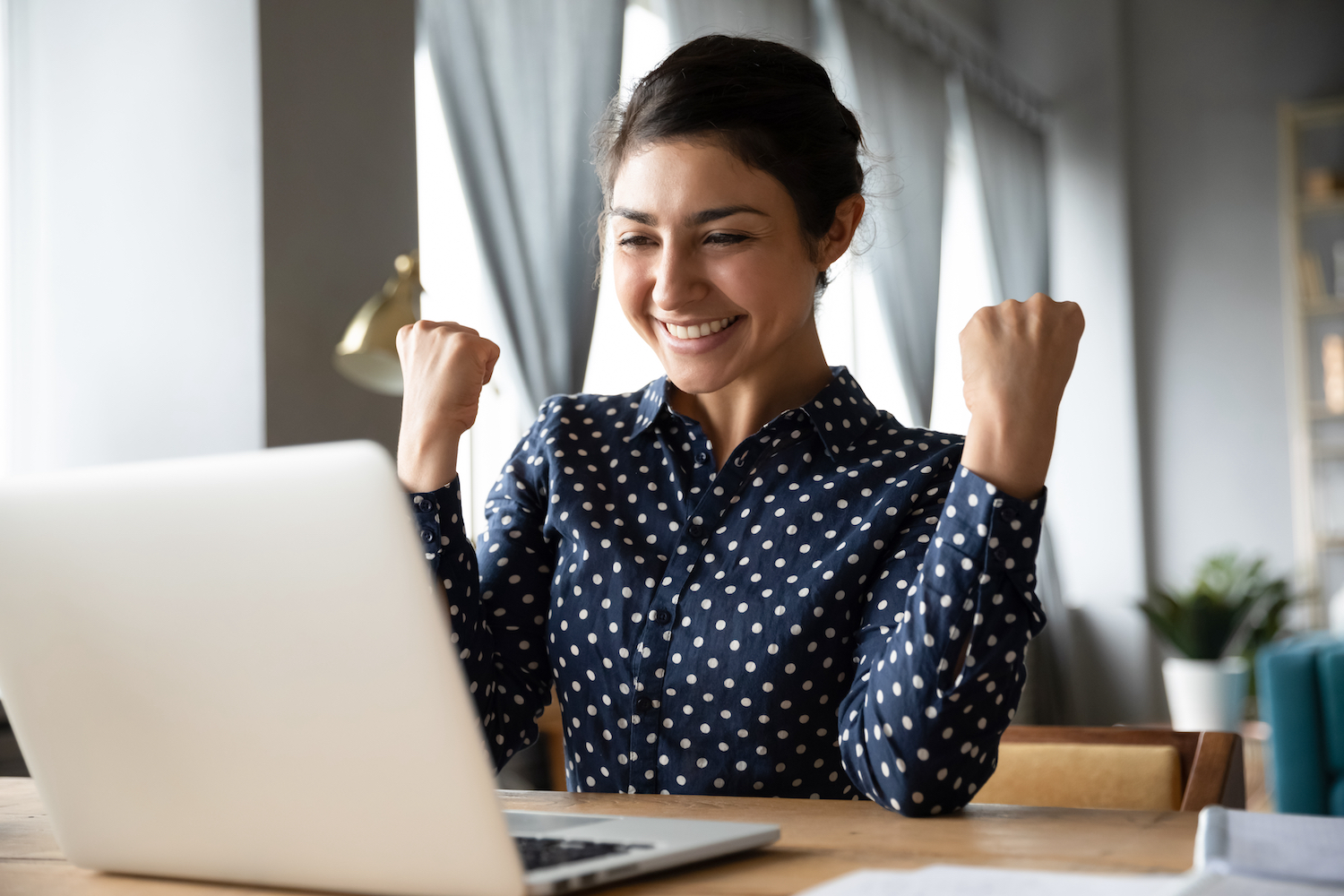 A young insurance agent cheering at a laptop after completing an online risk management certification