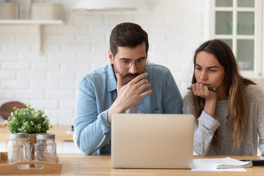 Two people looking at laptop screen learning about insurance lead management software