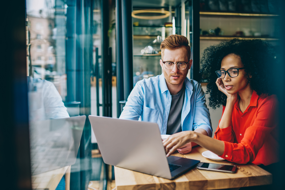 Two people learning on a laptop about lead management in insurance