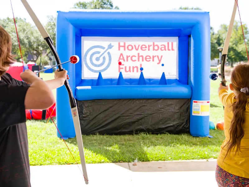 2 kids playing archery tag with a hoverball carnival game outdoors