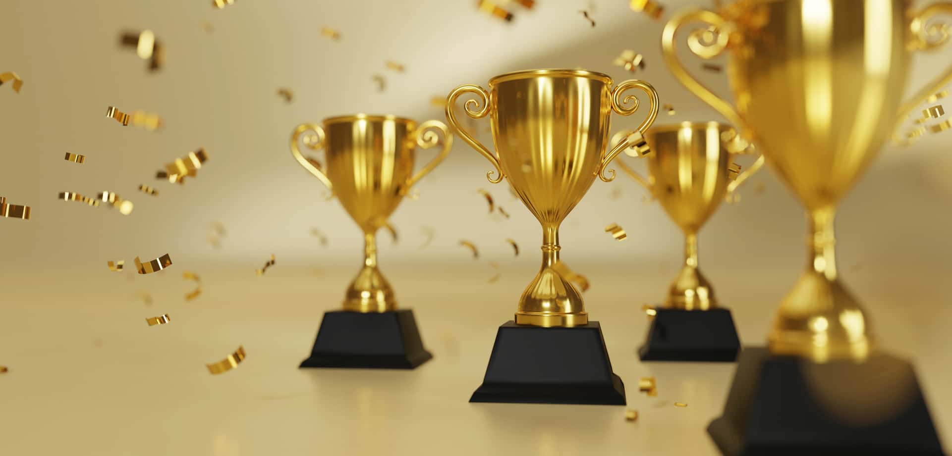 Several gold trophies with gold glitter cascading around