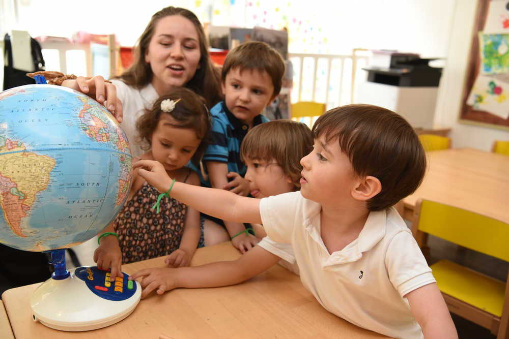 Children pointing out a globe in a kindergarten