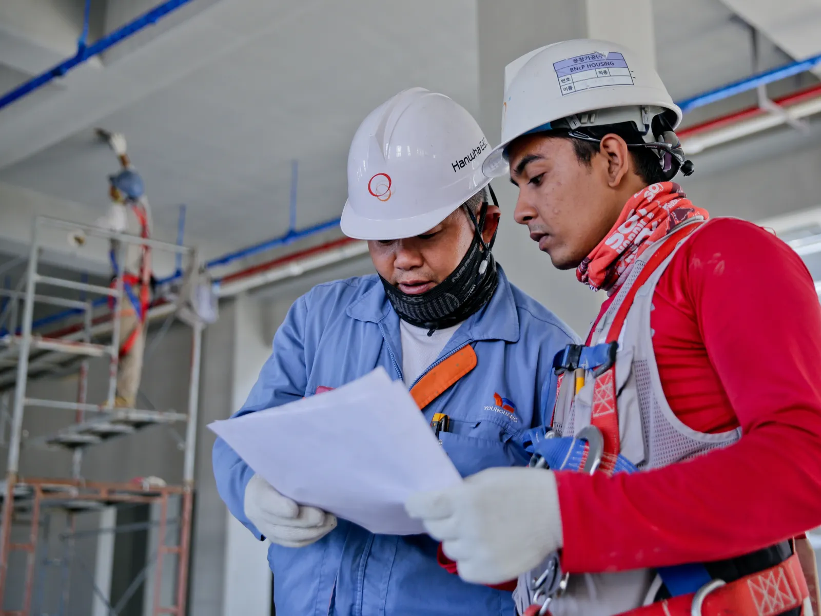 Two factory workers looking at the papers and discussing them