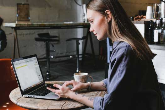 Foto de uma mulher concentrada mexendo em um computador em um café