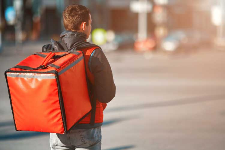 Foto de entregador com a bag de entrega nas costas em laranja